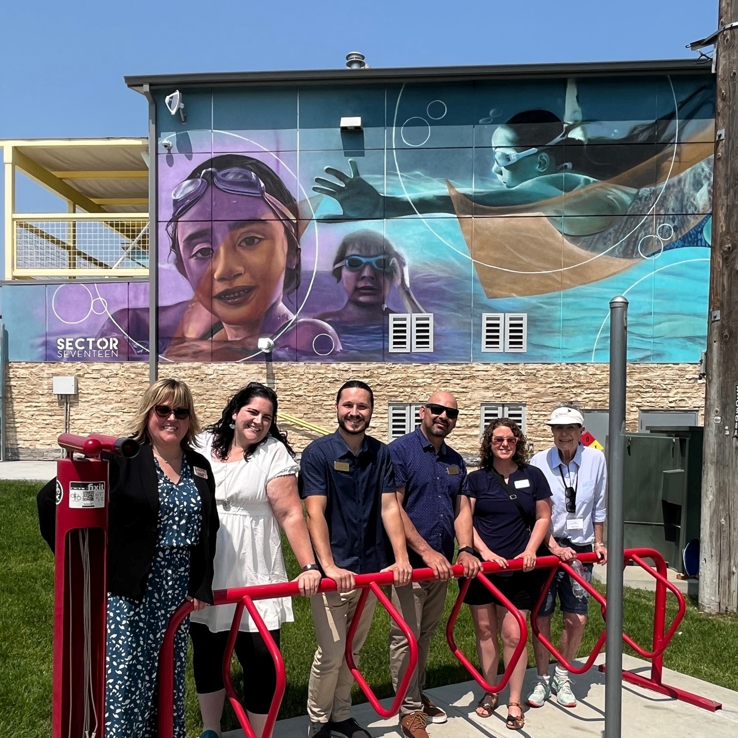 Arts Commissioners in front of mural of children swimming with abstract shapes at Meridian Community Pool