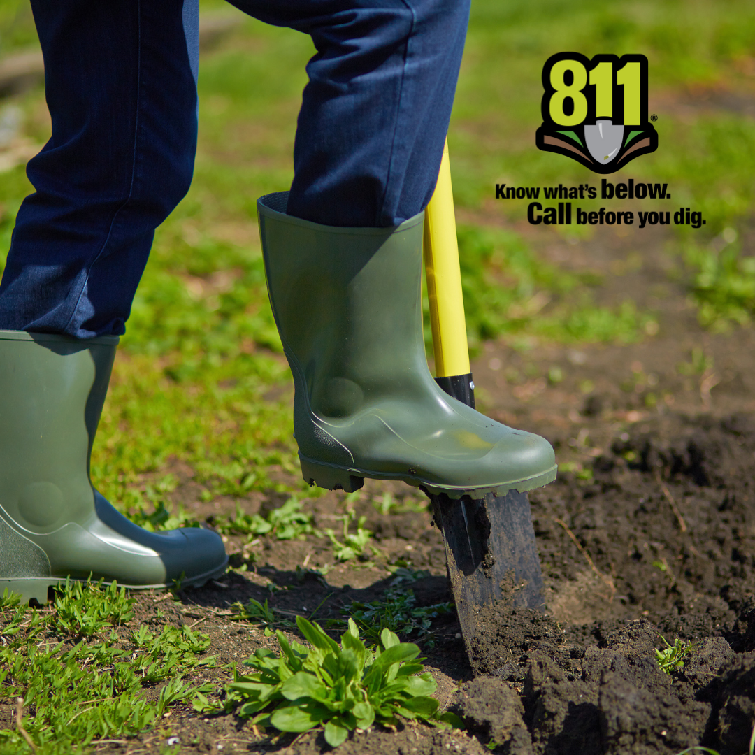 Person in boots with their foot on a shovel with 811 logo