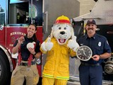 two firefighters standing with sparky the fire dog