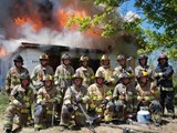 group photo of meridian firefighters in front of a burning house