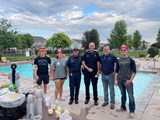 Police Captain, City Councilman, and citizens standing in front of a pool at a National Night Out party.