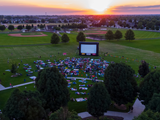 Aerial view of Settlers Park in the sunset with a crowd gathered for a movie night