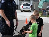 K9 Officer and his k9. Two young boys are petting the dog.