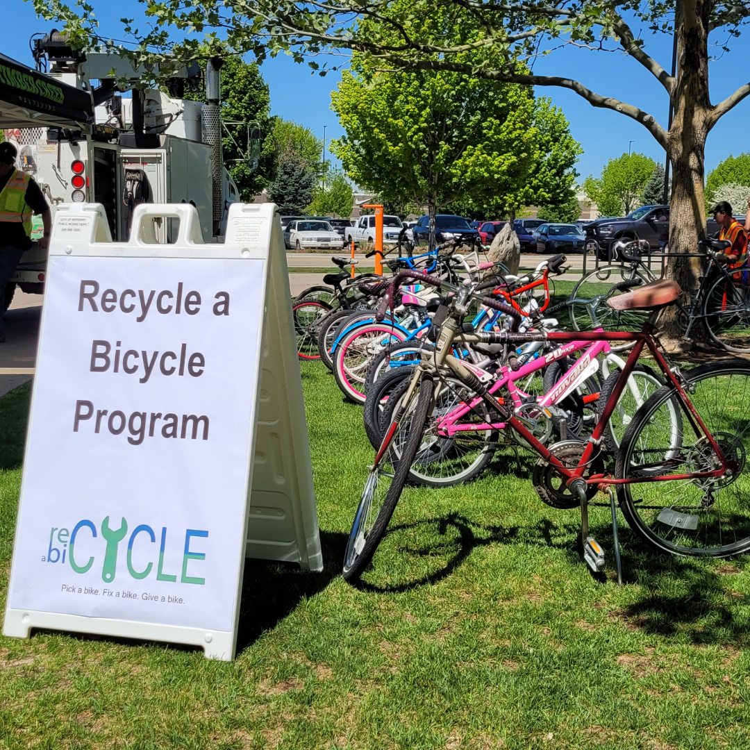 Refurbished bikes lines up on the grass with a Recycle a Bicycle Program sign