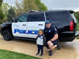 School Resource Officer and child posing in front of a police car.