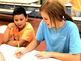 Counselor and camper writing at a desk
